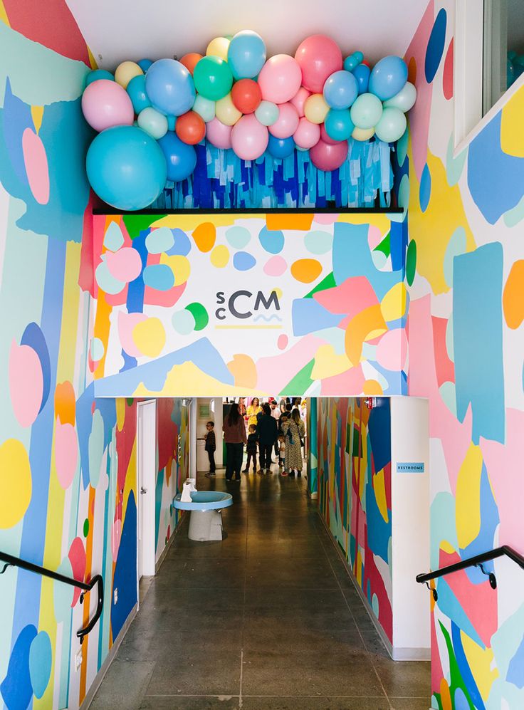 the entrance to an office building decorated with colorful balloons and streamers on the ceiling