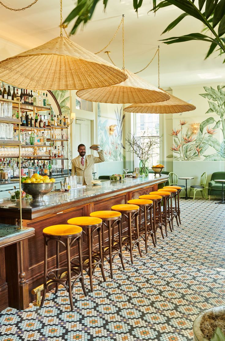 a bar with yellow stools and umbrellas hanging from it's ceiling in a restaurant