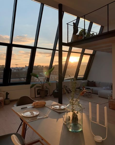 a dining room table with plates and glasses on it in front of large windows overlooking the city