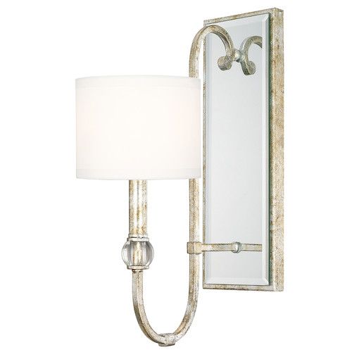 a wall light with a white shade on it's side and a mirror behind it