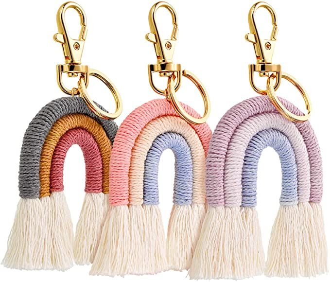 four key chains with tassels on each one in different colors and shapes, hanging from gold hooks