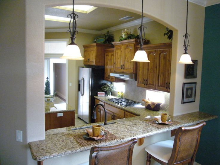 a kitchen with two bar stools next to an open floor plan and wooden cabinets