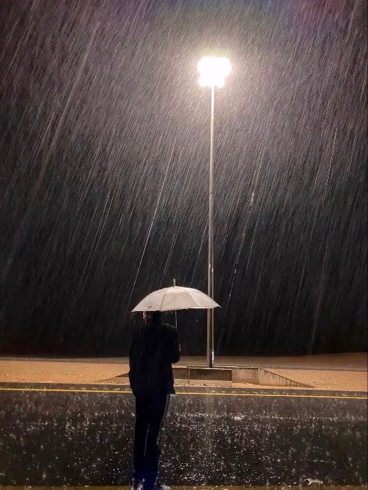 a person standing under an umbrella in the rain