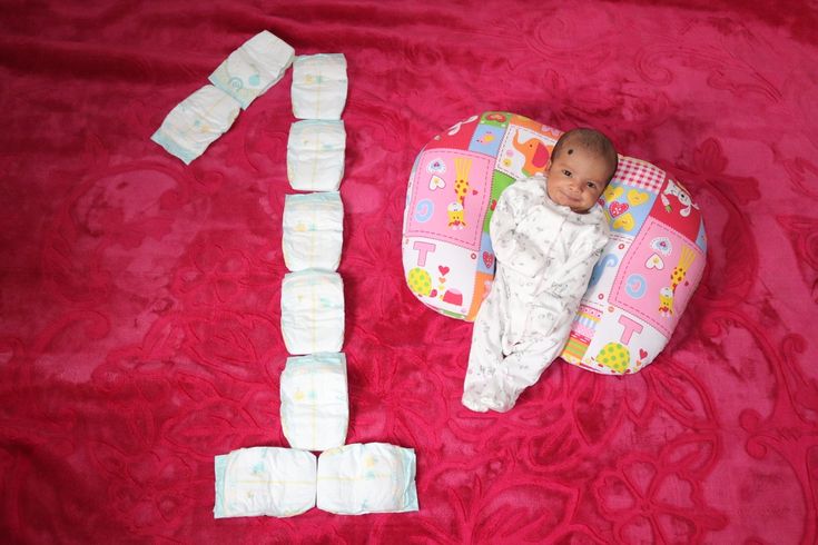 a baby laying on top of a pink blanket next to two pieces of diapers