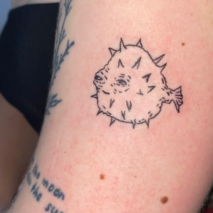 a tattoo on the arm of a person with a small puffer fish in it