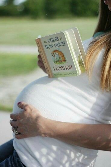 a pregnant woman reading a book while holding her belly up in front of the camera