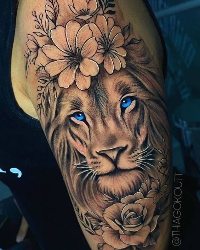 a woman's arm with a lion and flowers tattoo on her left arm, which has blue eyes