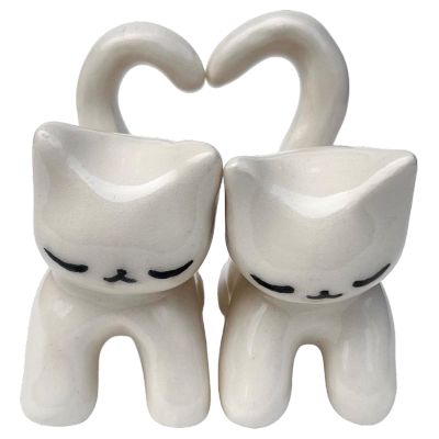 two white ceramic cat figurines in the shape of a heart