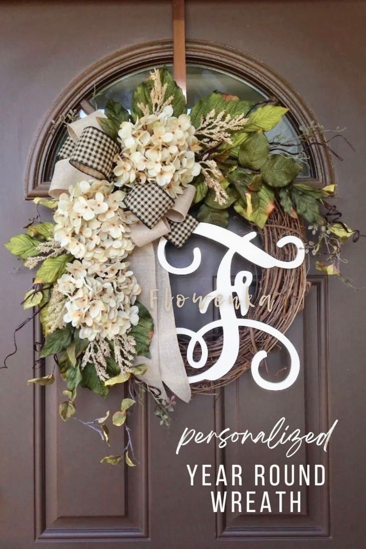 a wreath with the letter f on it and purple flowers is hanging from a front door