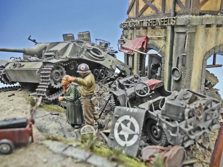 a couple of men standing in front of a destroyed up tank and other items on the ground