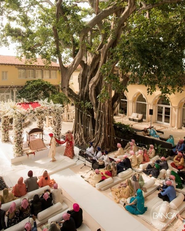 an outdoor ceremony with lots of people sitting on couches under the trees and in front of them