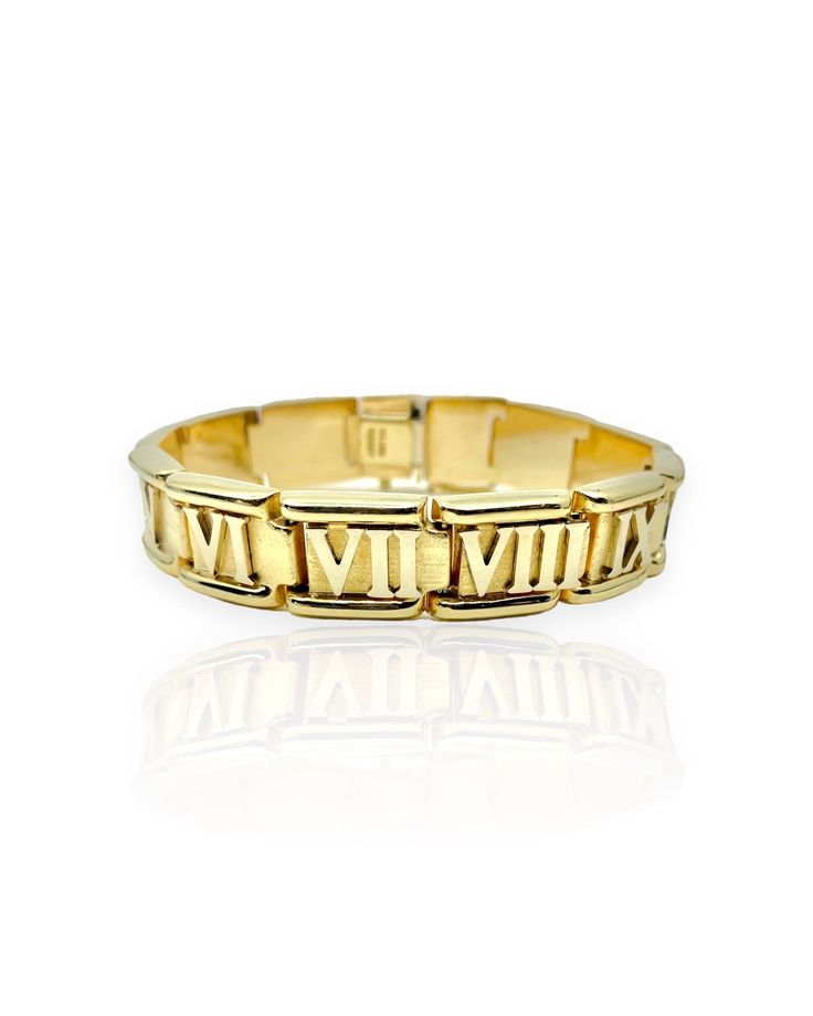 a yellow gold ring with roman numerals on the front and sides, set against a white background