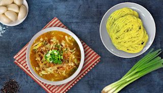 two bowls of soup, one with noodles and the other with green onions next to it