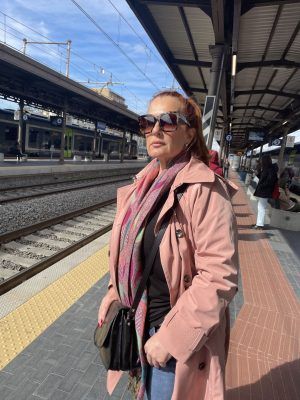 a woman standing on the side of a train track next to a train station platform