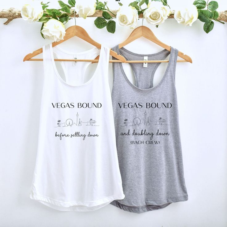 two women's tank tops hanging on a rack with white roses in the background