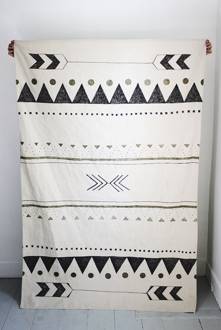 a black and white blanket hanging on the wall next to a door with an arrow design