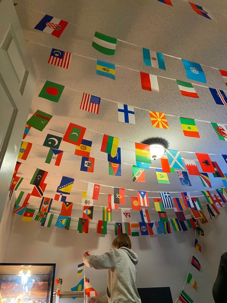 a person standing in front of flags hanging from the ceiling