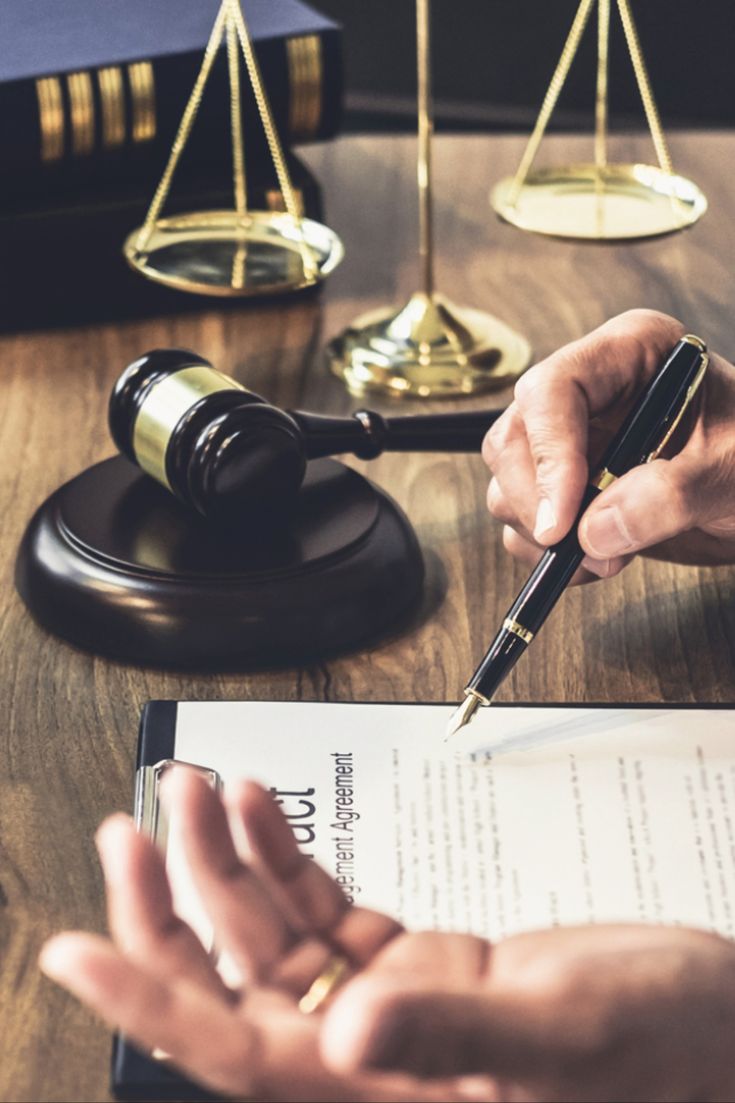 a person holding a pen and writing on paper next to a judge's gavel