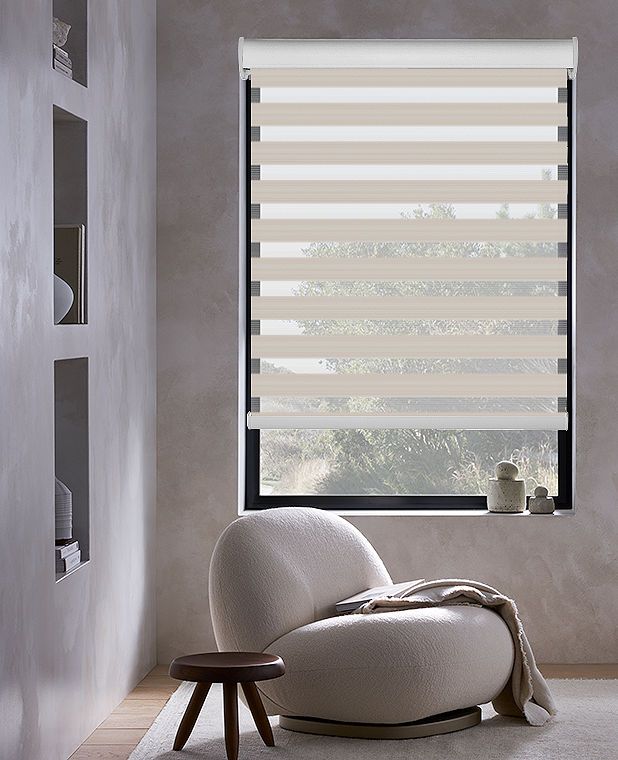 a living room with a chair and window covered in blinds