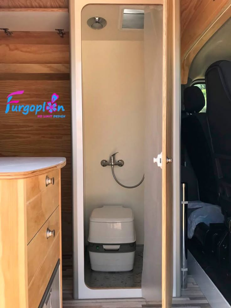 the interior of an rv with its door open and toilet in the back ground next to it