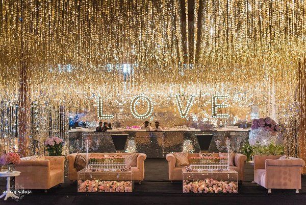 a stage set up with couches, chairs and flowers on the floor in front of a love sign