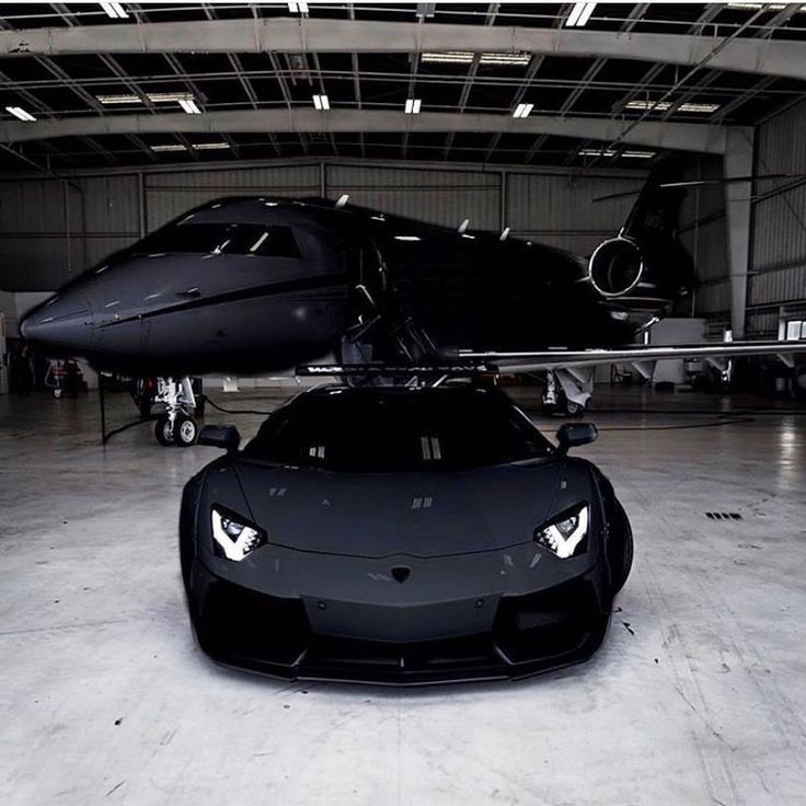 a black sports car parked in front of an airplane