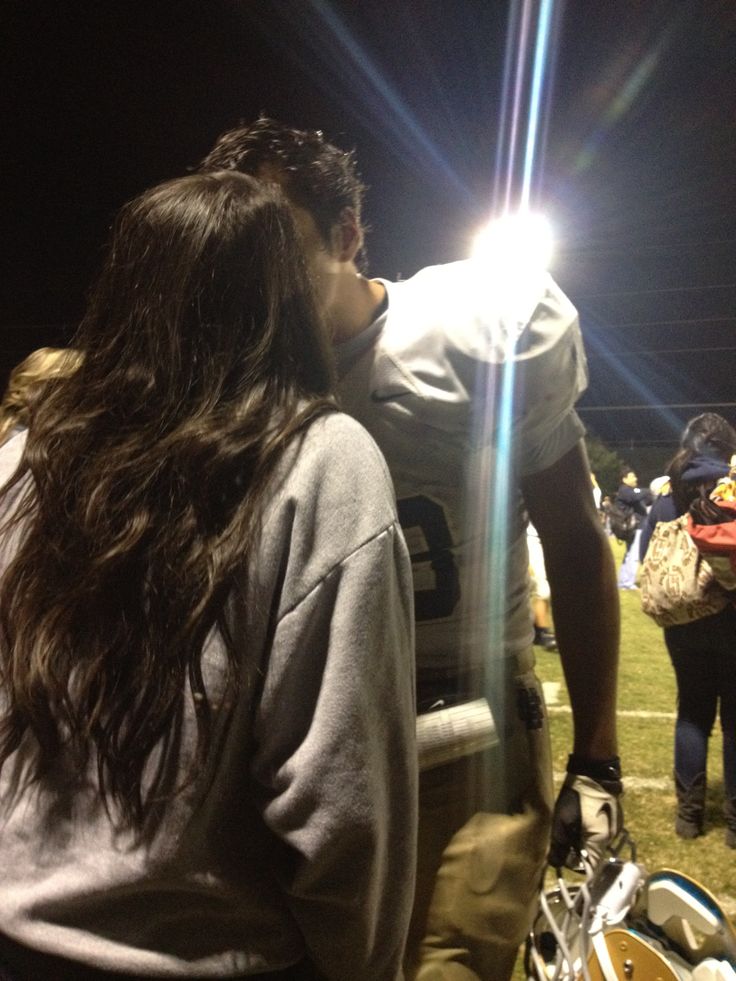 a man kissing a woman on the sidelines at a football game in black and white