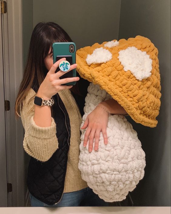 a woman taking a selfie in front of a mirror wearing a crocheted hat