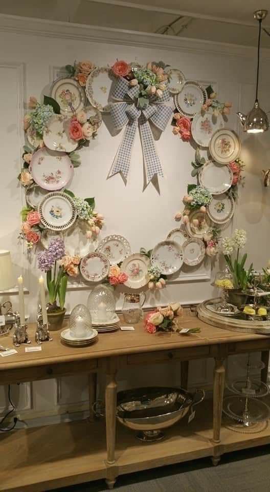 a table topped with plates and flowers on top of a wooden shelf next to a wall