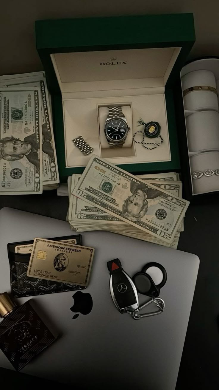 an apple laptop computer sitting on top of a table next to money and other items