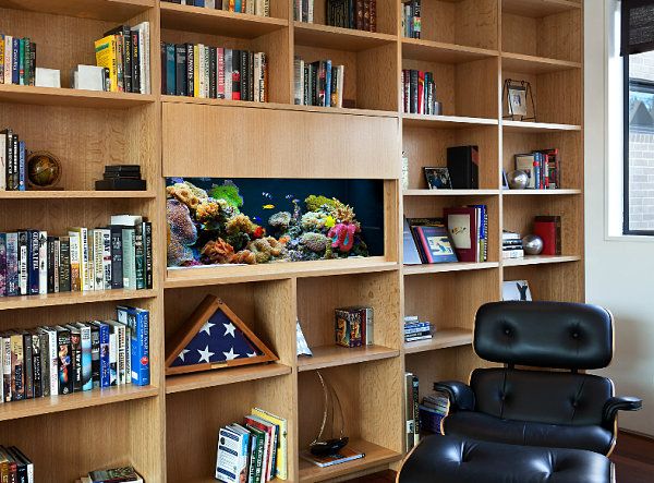 a living room filled with lots of bookshelves and a black chair in front of it