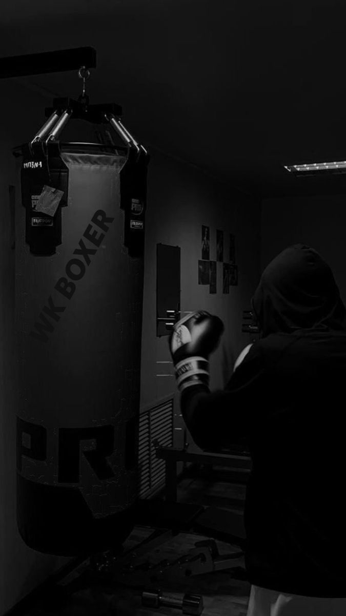 a person wearing boxing gloves in a black and white photo with a punching bag on the wall