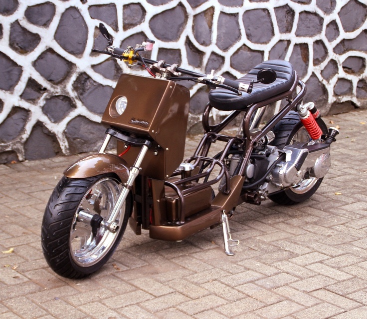 a brown motorcycle parked on top of a brick floor next to a stone wall and fence