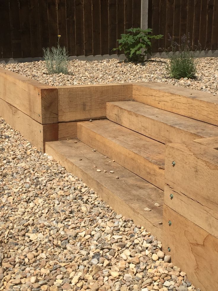 wooden steps leading up to the side of a building with gravel and rocks around them