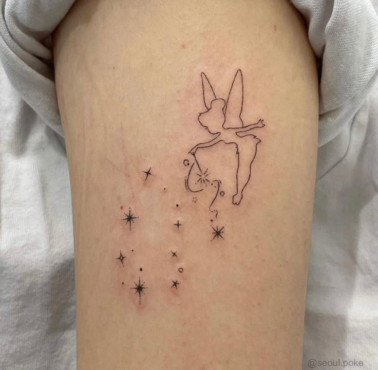 a small tattoo on the back of a woman's arm, with stars and a fairy