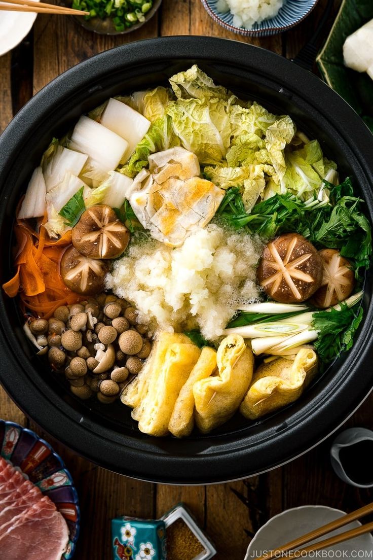 a bowl filled with different types of food and chopsticks on top of a wooden table