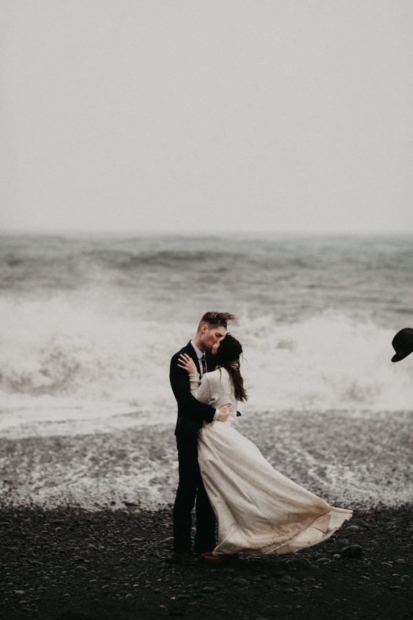 a bride and groom embracing on the beach