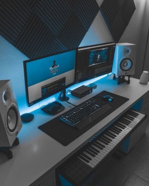 a computer desk with two monitors, keyboard and speakers next to each other on it