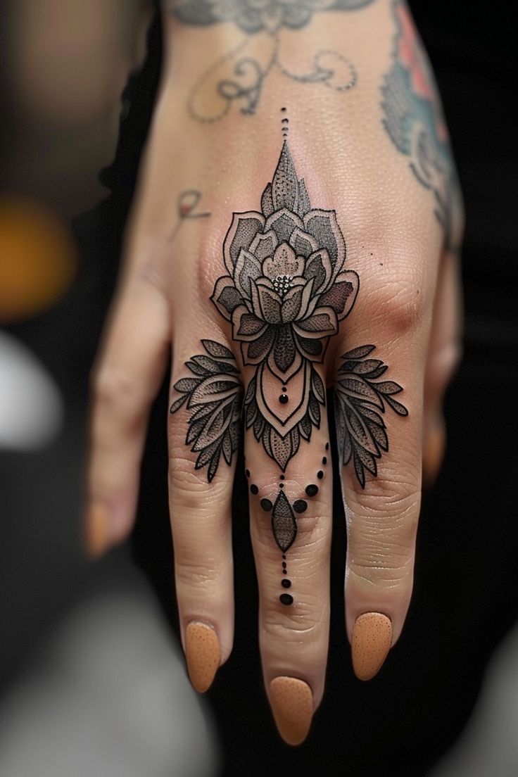 Hand with an intricate black and gray flower tattoo covering the entire back, extending to the middle finger, adorned with detailed patterns and dots. Thumb Palm Tattoo, Womens Thumb Tattoos, Woman Knuckle Tattoos, Creative Finger Tattoos, Finger Tattoos Taurus, Finger Mandala Tattoo, Funny Hand Tattoos, Whimsical Hand Tattoo, Flower Finger Tattoos For Women