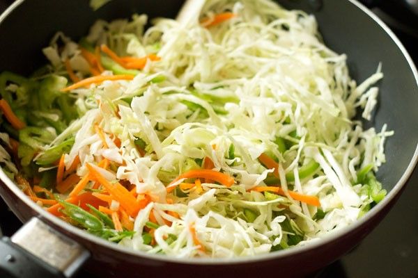 shredded carrots, celery and cabbage cooking in a pan on the stove