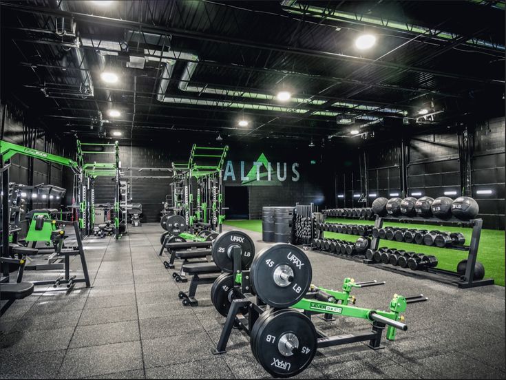 an indoor gym with rows of green and black dumbbells, barbells, and weight racks