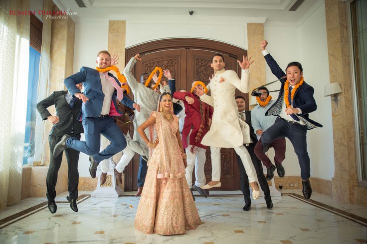 a group of men and women jumping in the air with their hands up while wearing tuxedos