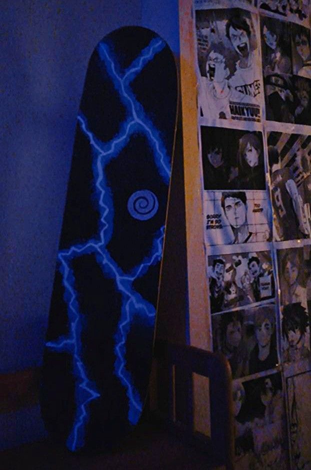 a skateboard is next to a wall with pictures on it in the dark room