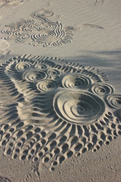 an intricately designed sand sculpture on the beach with circles and waves in the sand