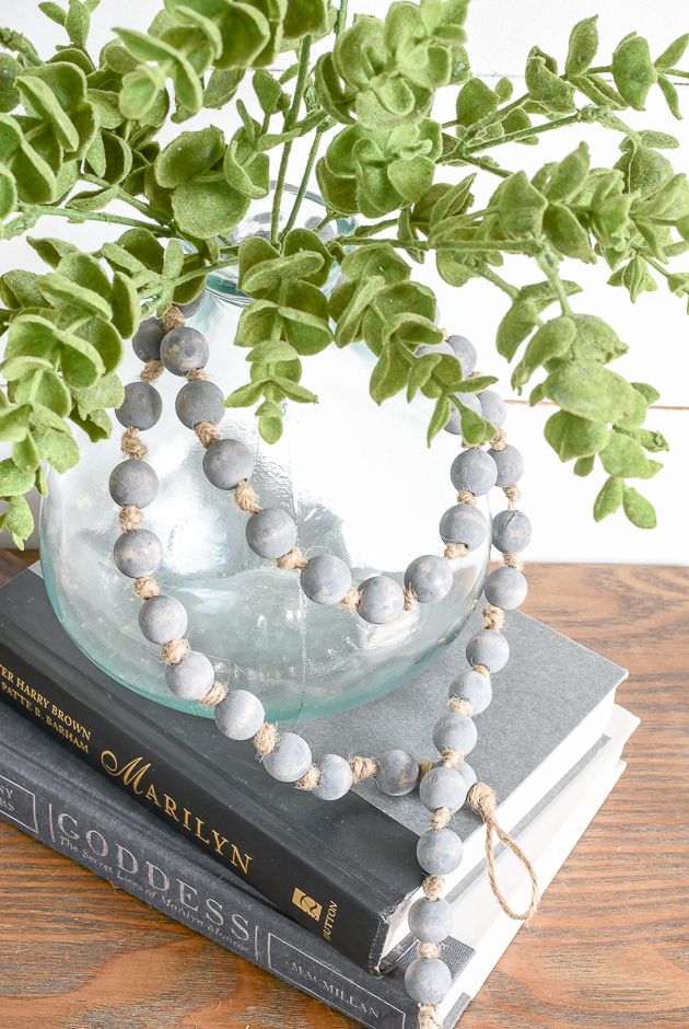 a vase filled with green leaves sitting on top of two books next to a plant