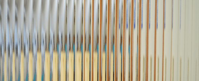 an abstract photograph of thin lines in blue, yellow and white colors on a wall