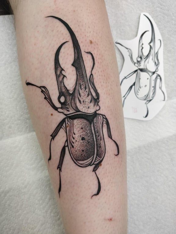 a black and white beetle tattoo on the leg