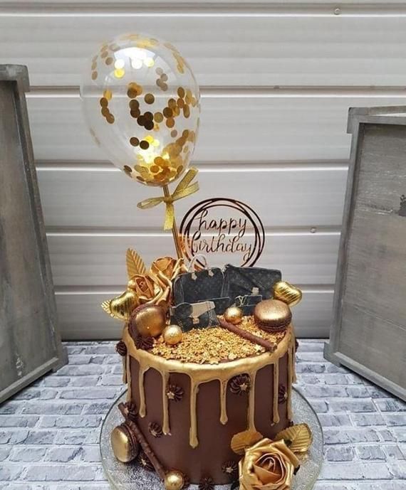 a chocolate cake with gold decorations and balloons