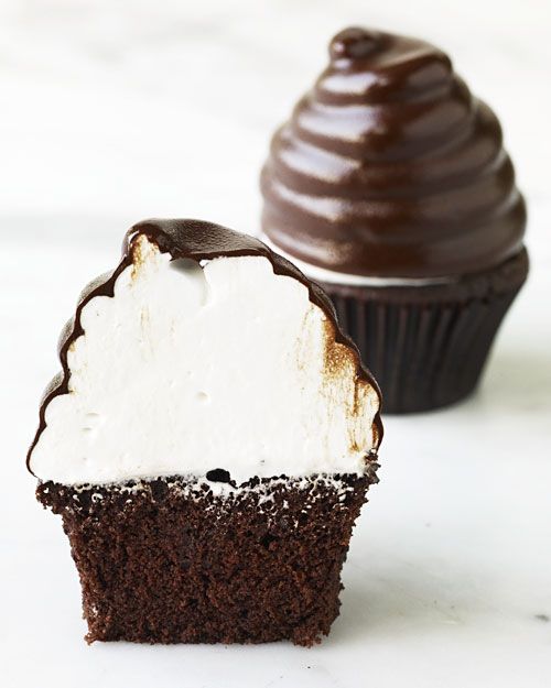 two chocolate cupcakes with white frosting and one has a bite taken out