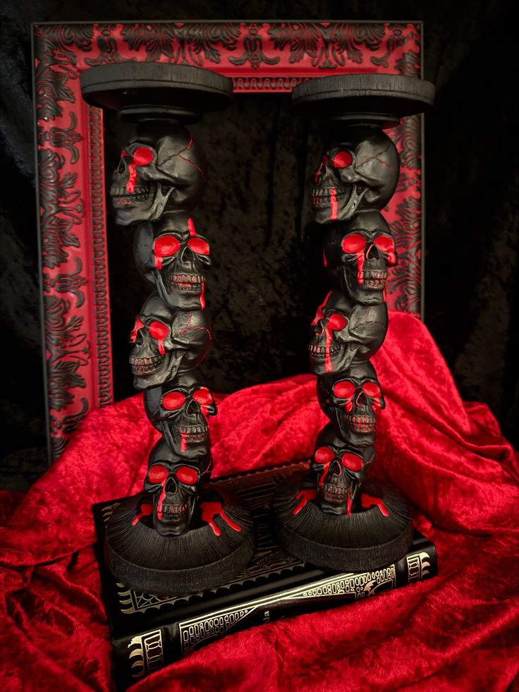 two black skulls with red eyes are standing next to each other in front of a book